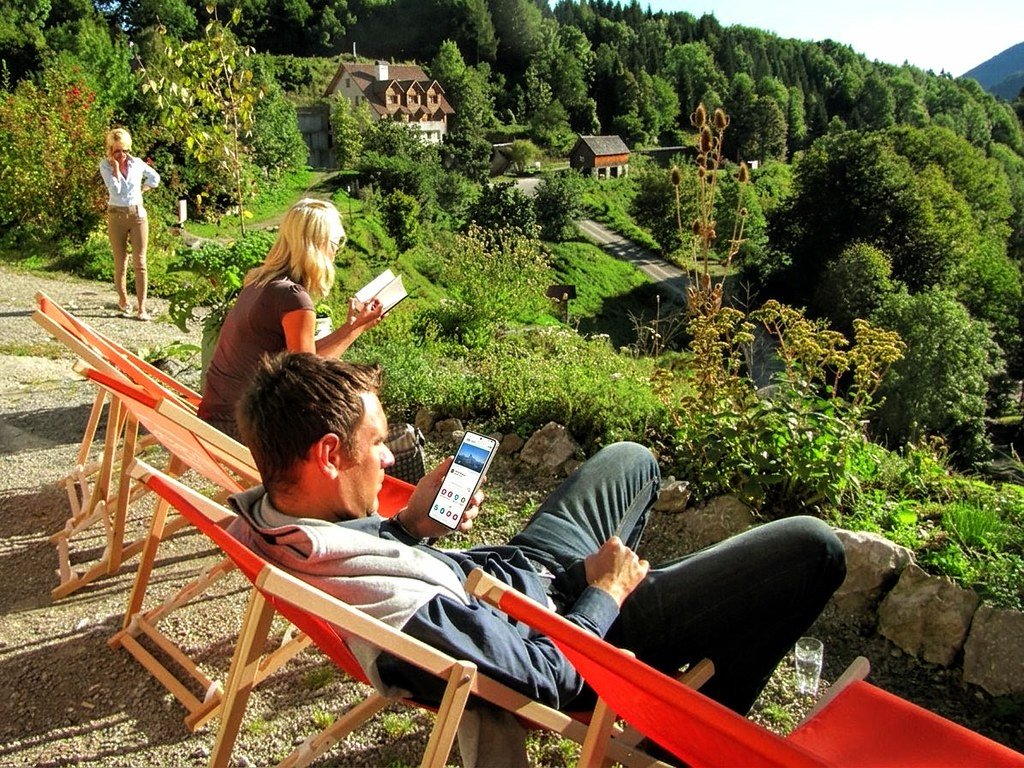 Pause beim Seminar in der Natur am Liegestuhl mit modernem Smartphone